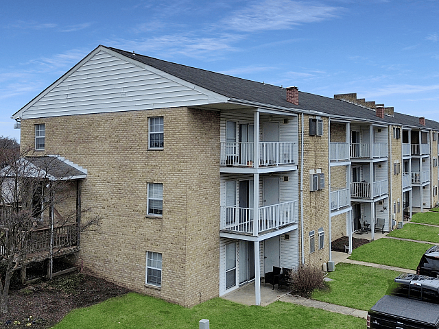 Charming apartment building with spacious balconies, nestled in a peaceful neighborhood with well-maintained green lawns.