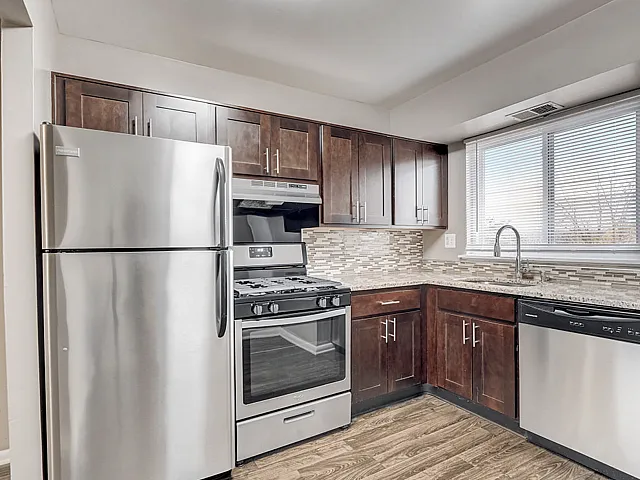 Modern kitchen with stainless steel appliances, elegant dark wood cabinets, and a large window providing ample natural light.