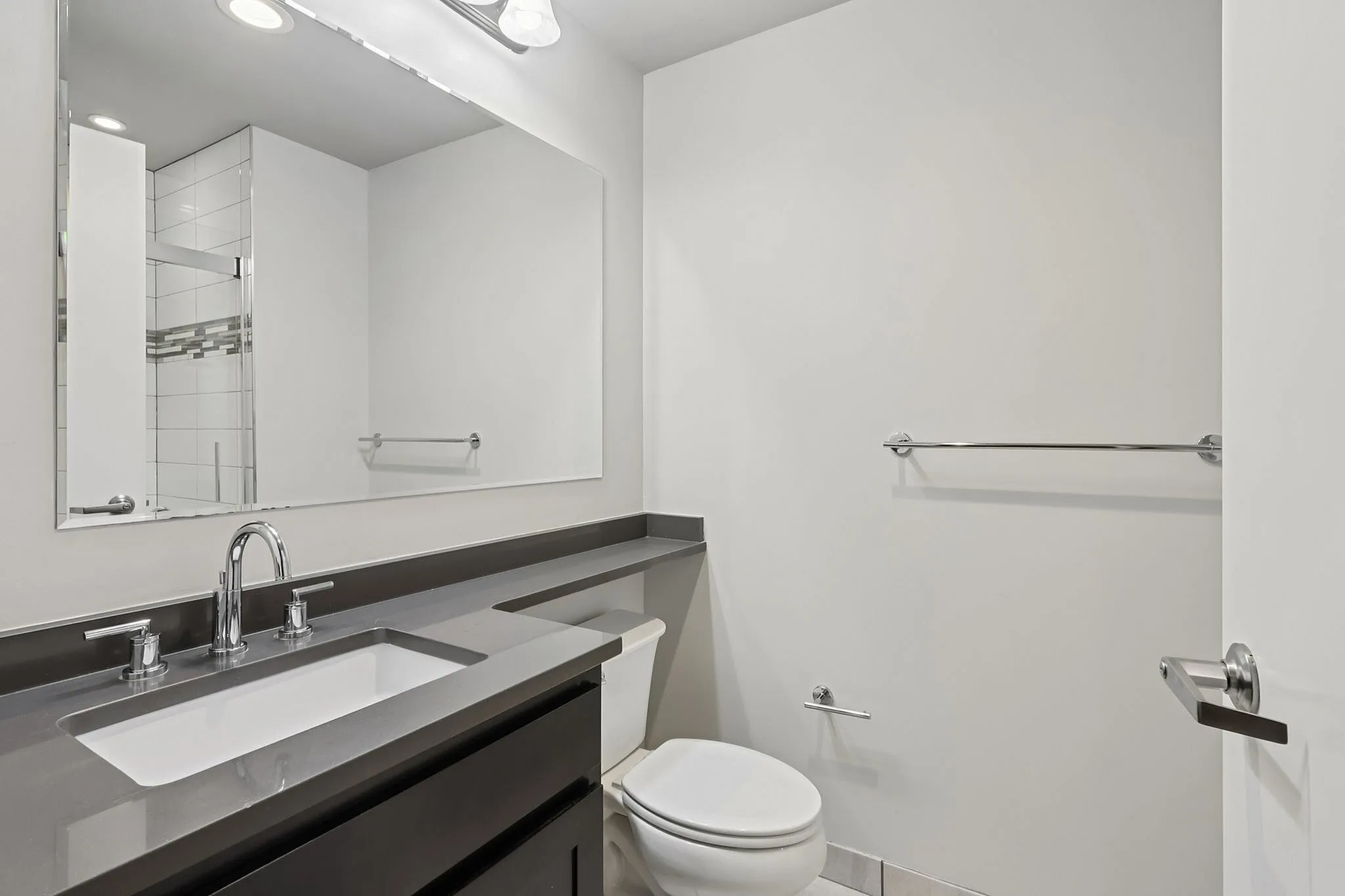 Modern bathroom with sleek fixtures, large mirror, and elegant tiled shower.