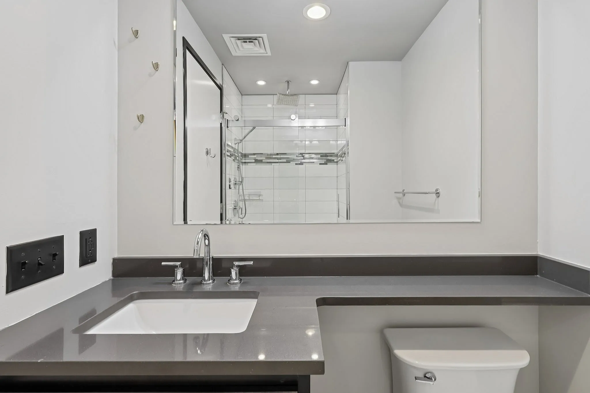 Modern bathroom with sleek vanity, elegant sink fixtures, and a glass-enclosed shower.