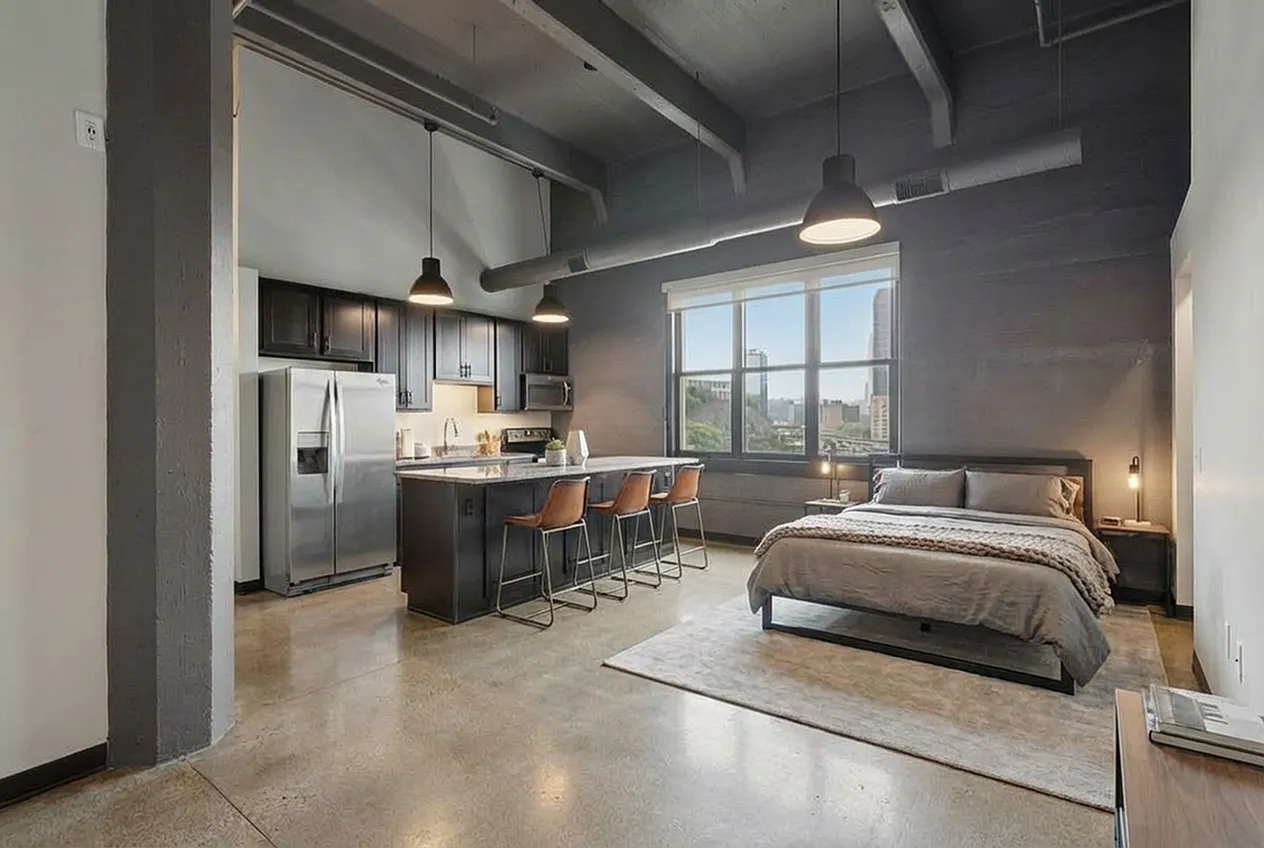 Chic urban studio featuring an open-concept layout with a sleek kitchen, cozy bedroom area, and expansive city views.