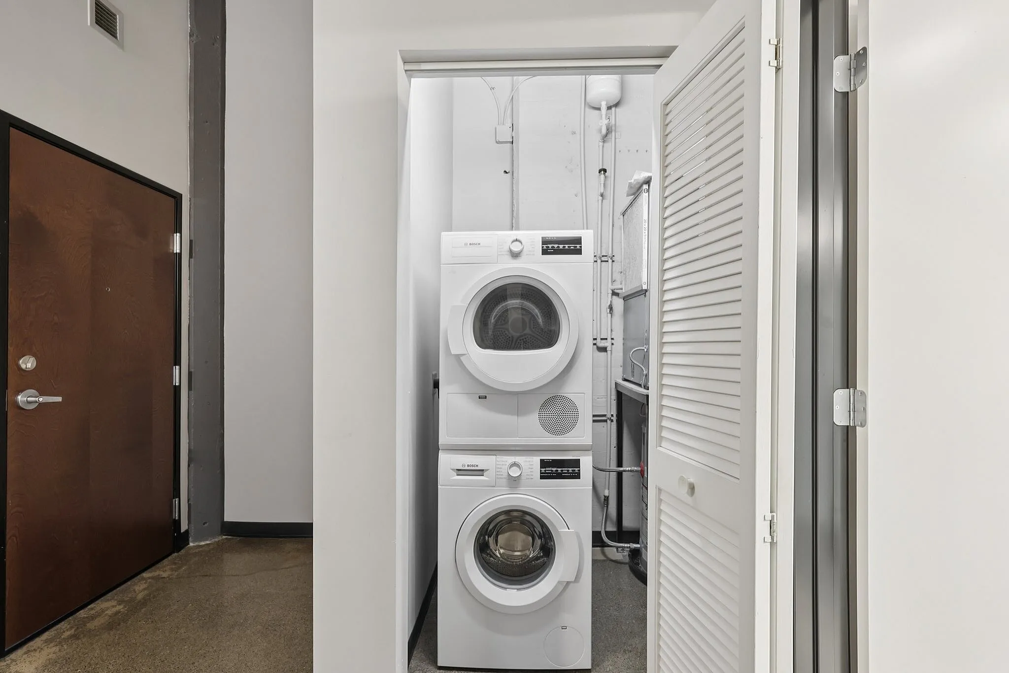 Sleek and modern laundry area with stacked washer and dryer in a stylish apartment setting.