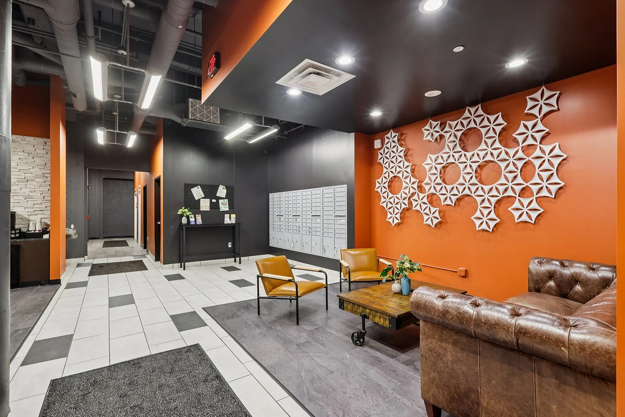 Chic lobby with modern decor featuring geometric wall art, leather seating, and bright lighting, creating a welcoming entrance.