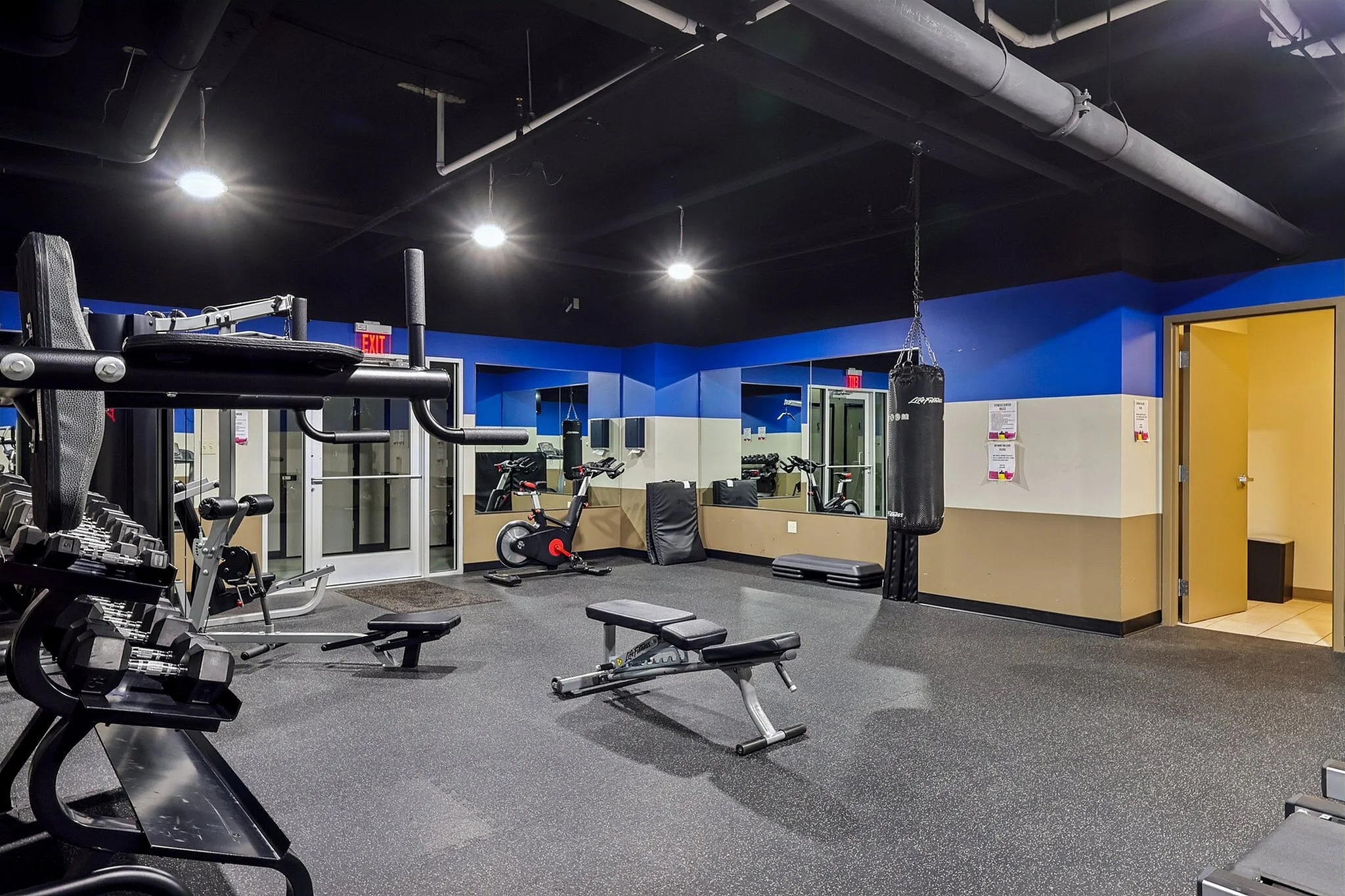 Modern fitness center featuring state-of-the-art equipment, free weights, and a punching bag, ideal for a complete workout experience.