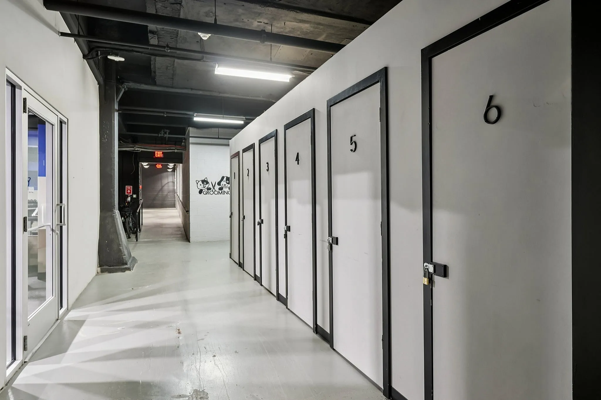 Modern industrial hallway with numbered storage doors and grooming area signage.