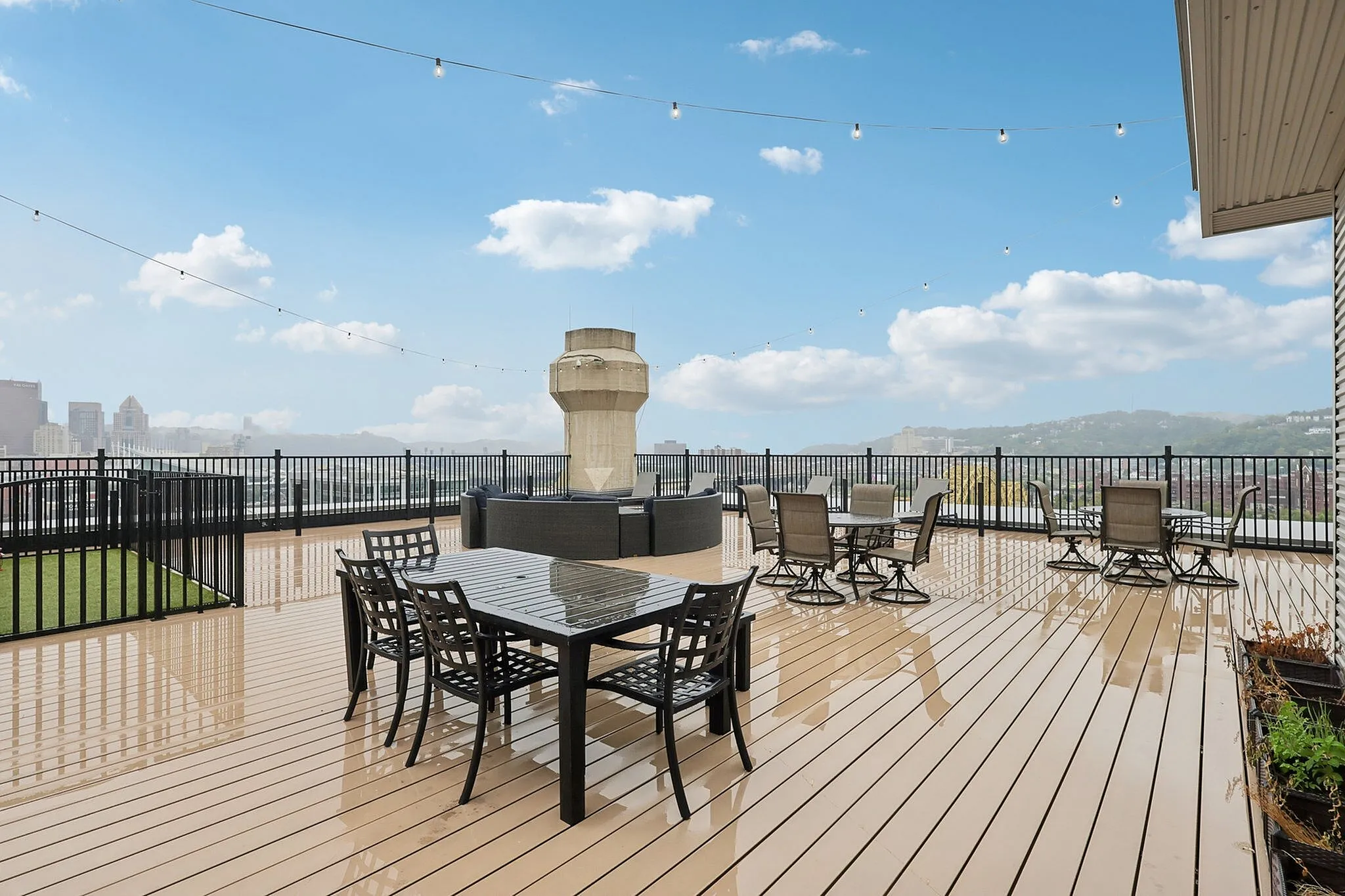 Expansive rooftop patio with modern seating, string lights, and stunning city skyline views.