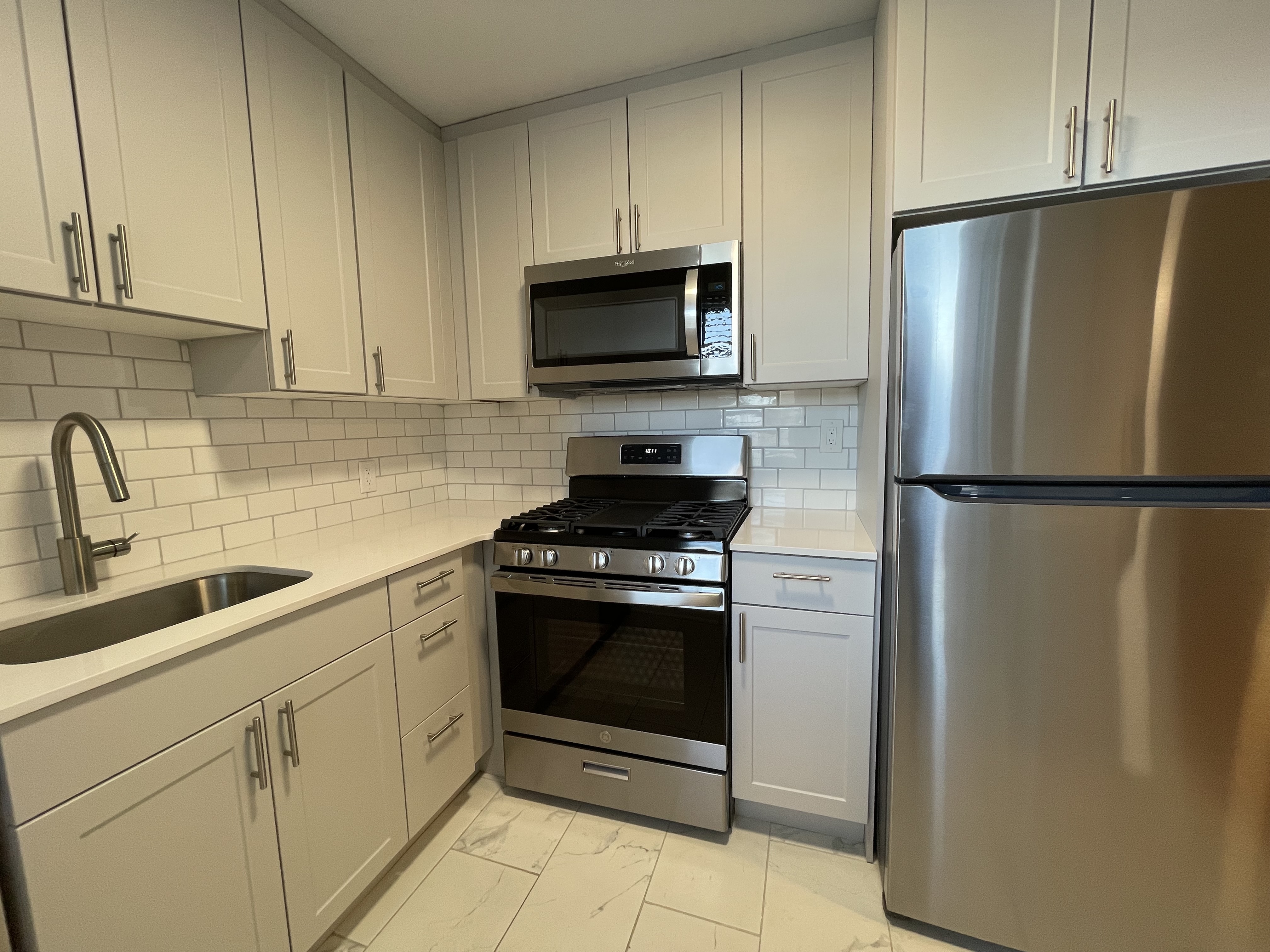 Modern kitchen with sleek stainless steel appliances, white cabinetry, and subway tile backsplash.