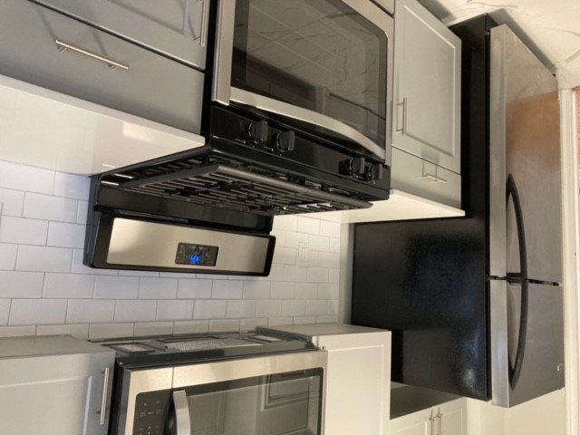 Modern kitchen with sleek stainless-steel appliances, subway tile backsplash, and elegant cabinetry.