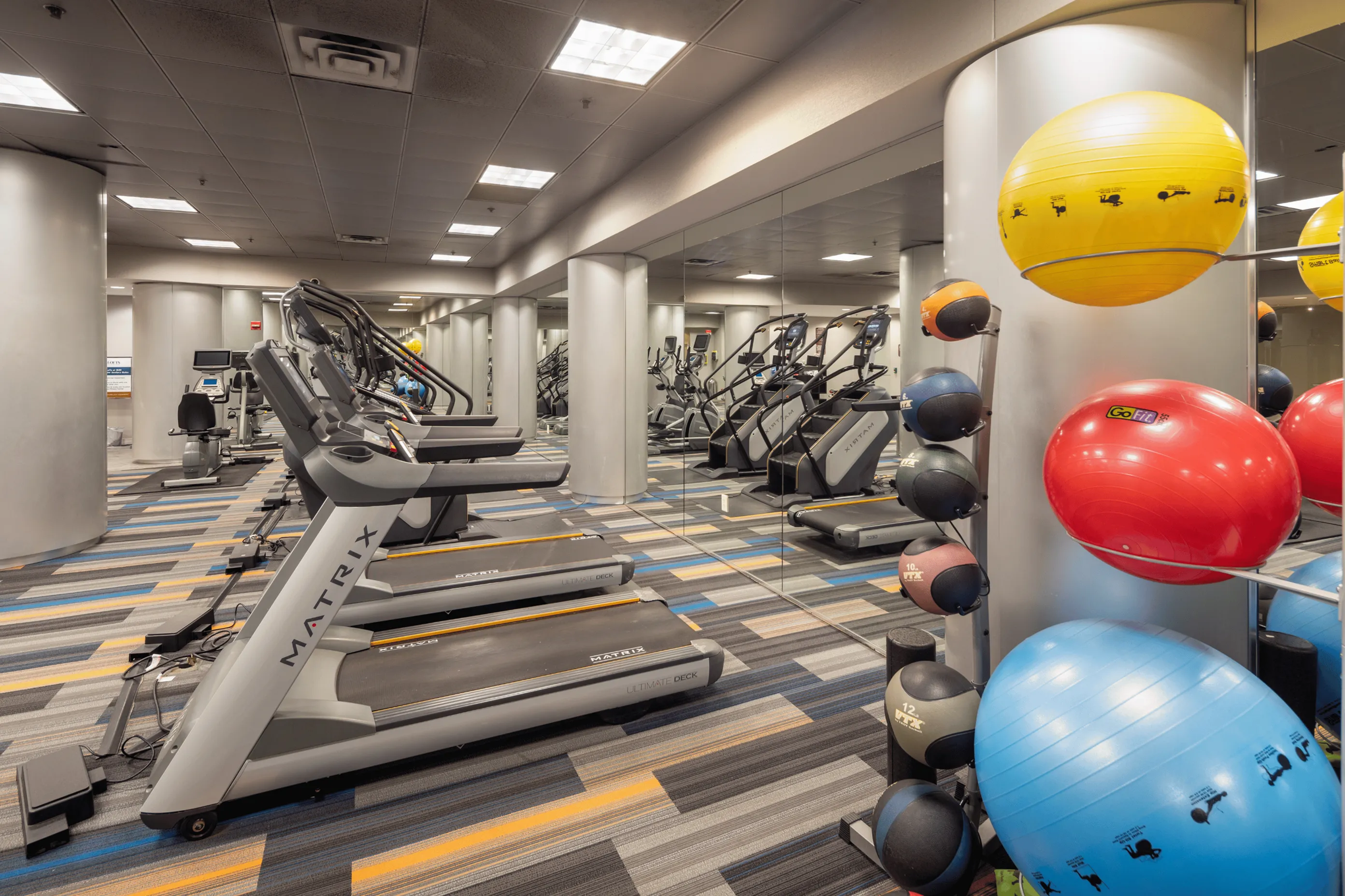 Modern fitness center with top-of-the-line treadmills, colorful exercise balls, and sleek mirrors for an energetic workout experience.