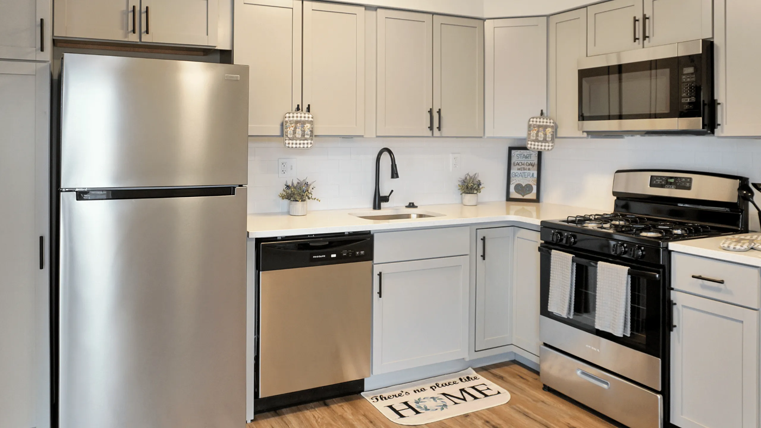 Modern kitchen with stainless steel appliances, chic cabinetry, and hardwood flooring.