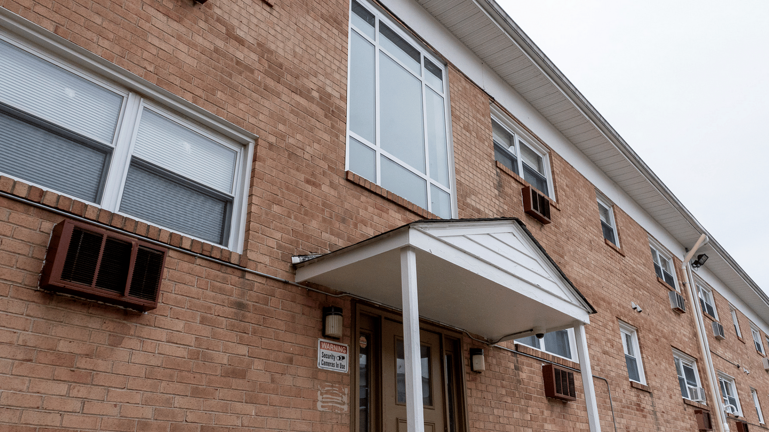 Brick apartment building with an inviting entrance and large windows.