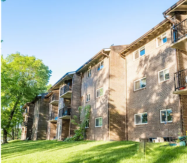 Charming brick apartment building with balconies and lush green surroundings.