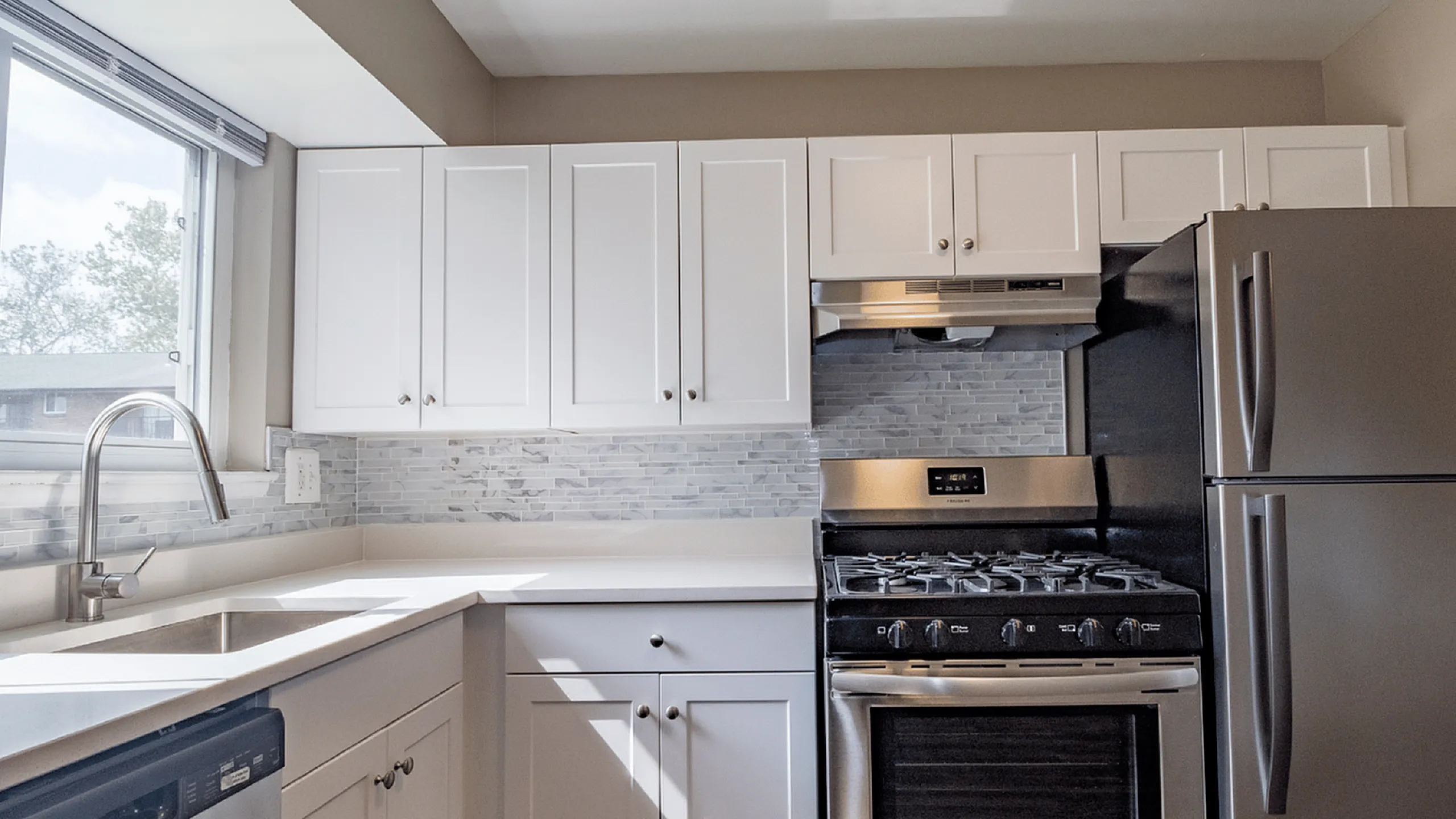 Bright modern kitchen with stainless steel appliances and white cabinetry.