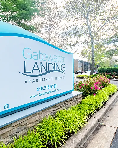 Vibrant entrance sign for Gatewater Landing Apartment Homes, surrounded by lush greenery and flowers.