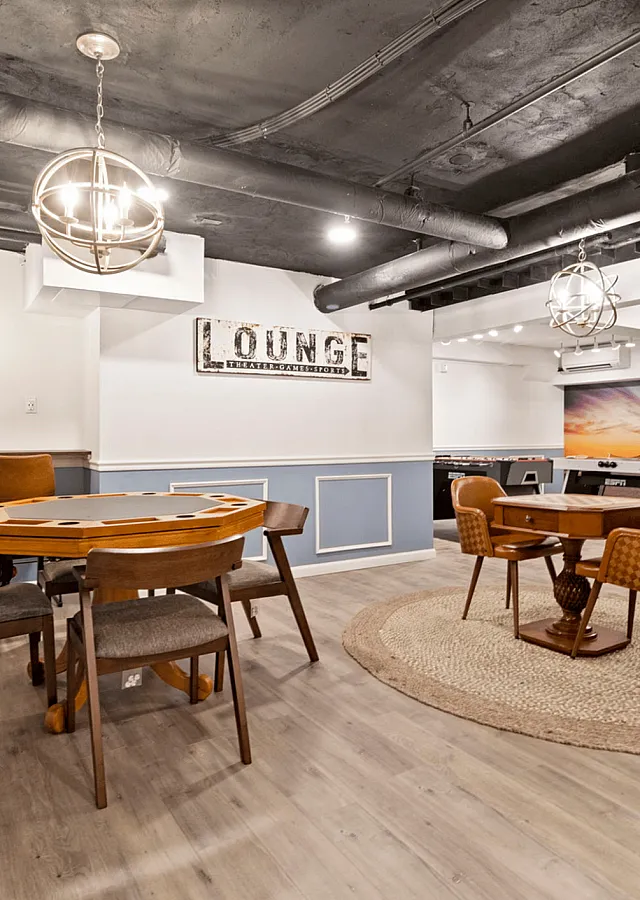 Stylish basement lounge with modern decor, featuring a gaming table and comfortable seating.