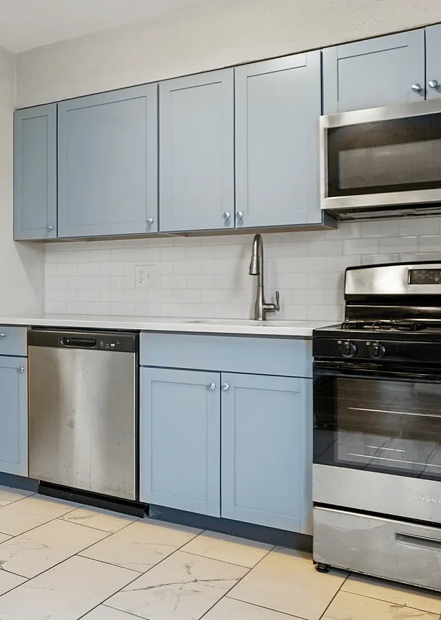 Sleek modern kitchen with light blue cabinets, stainless steel appliances, and stylish tile flooring.