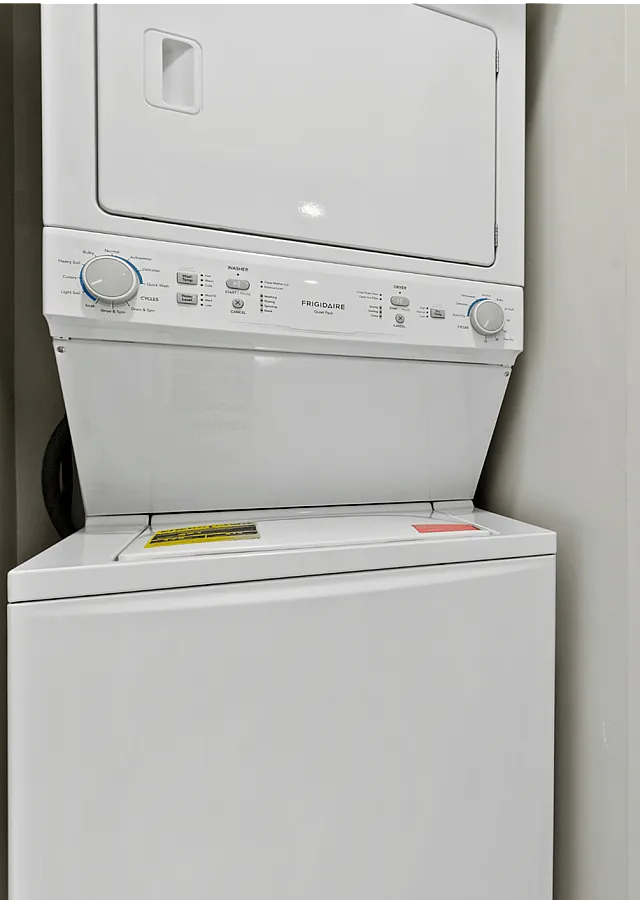 Modern apartment laundry area with a stacked washer and dryer beside a compact bathroom.