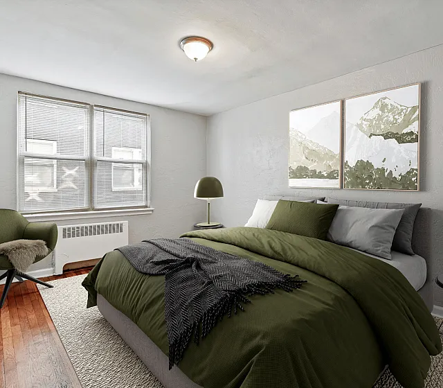 Inviting bedroom with chic decor, featuring a green bedspread, stylish armchair, and landscape artwork.