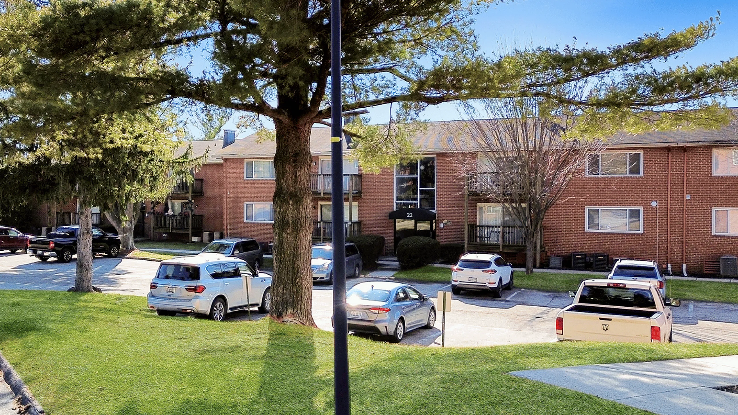 Inviting apartment building surrounded by lush greenery and parked cars on a sunny day.