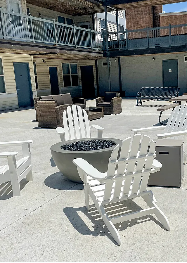 Inviting apartment courtyard with Adirondack chairs, fire pit, and comfortable seating area.