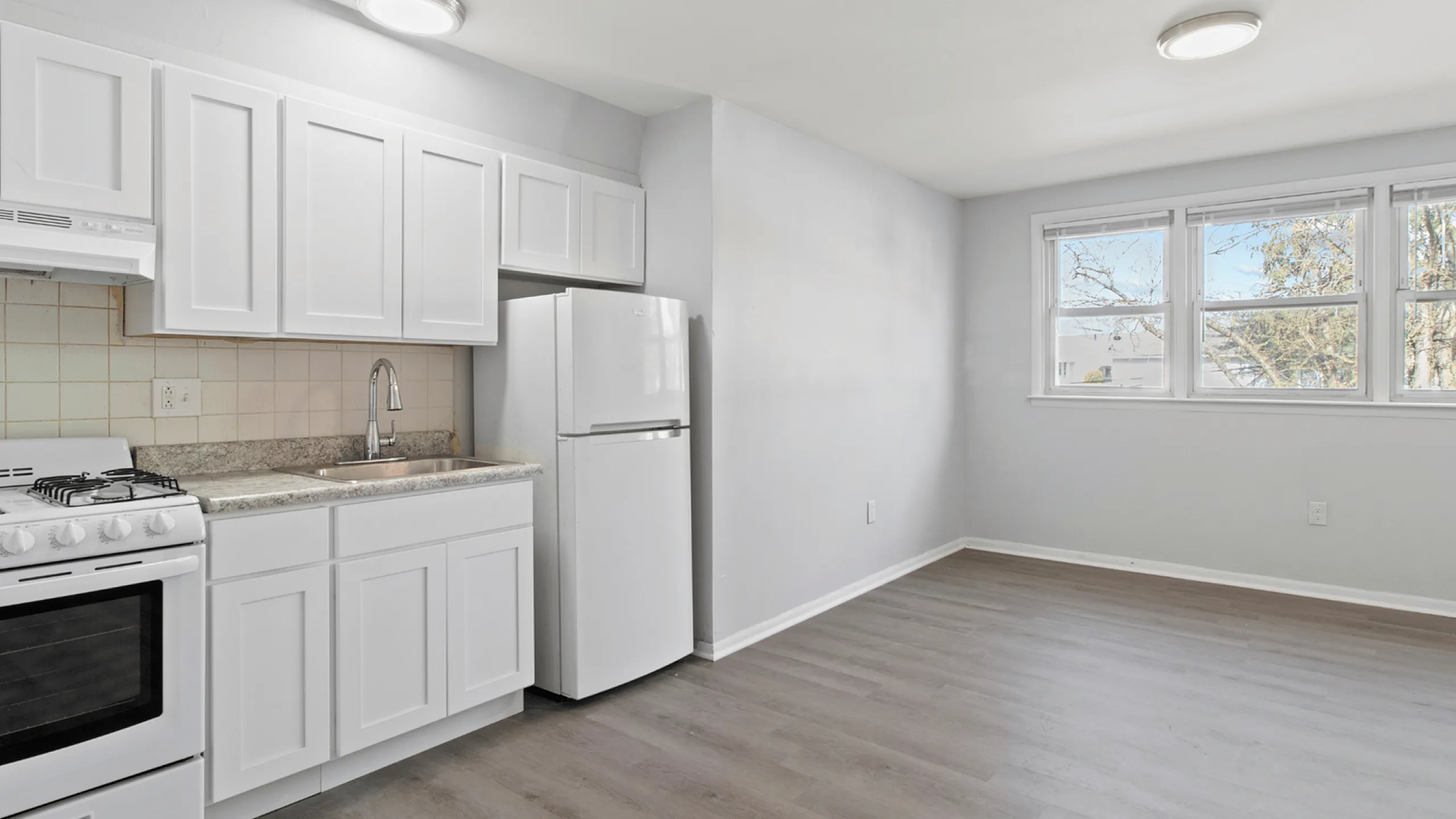 Inviting kitchen with white cabinetry, stainless steel sink, and large windows providing natural light.
