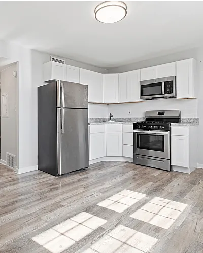 Bright kitchen with modern stainless steel appliances and stylish wood flooring.