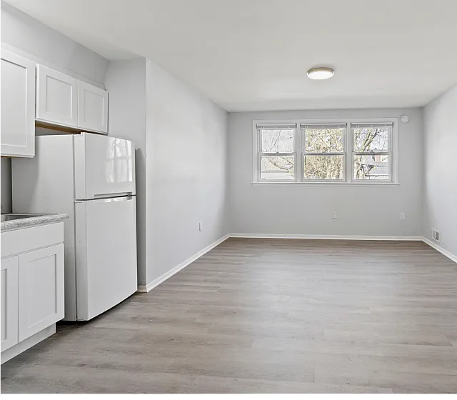 Spacious apartment with large windows, light wood flooring, and modern kitchen layout.