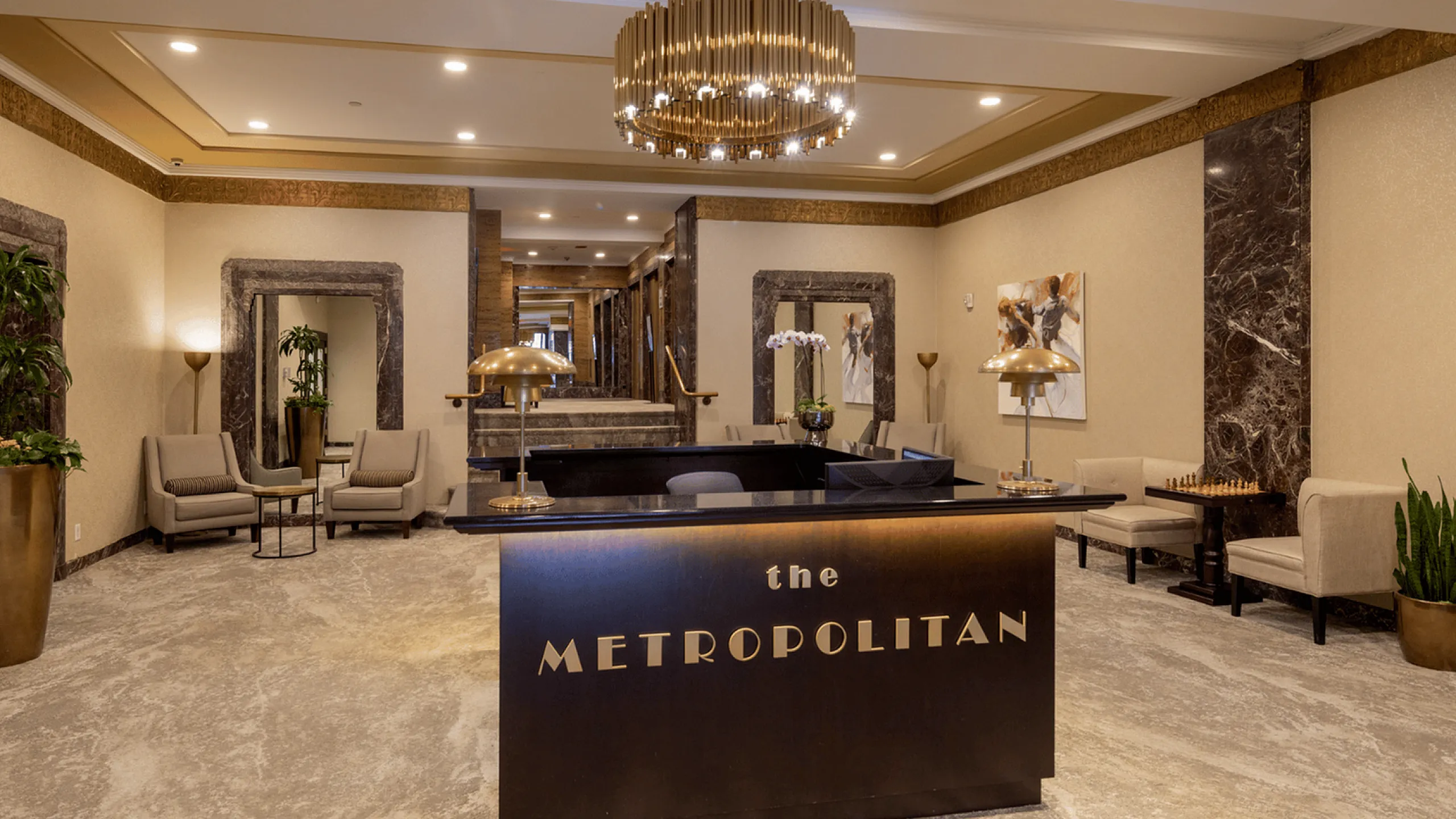 Luxurious hotel lobby of The Metropolitan with modern seating, large golden chandelier, and stylish decor.