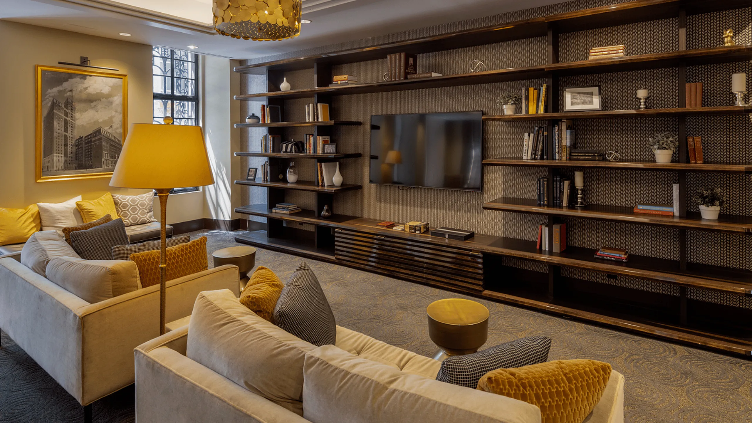 Chic living room with stylish sofas, a large bookshelf, a modern lamp, and a mounted TV.