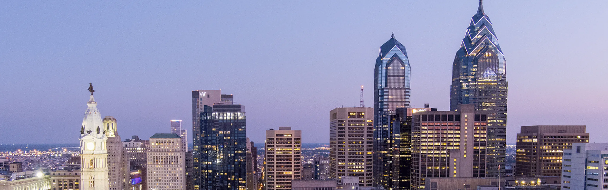 Stunning aerial view of a city skyline at dusk showcasing illuminated skyscrapers and historic architecture.