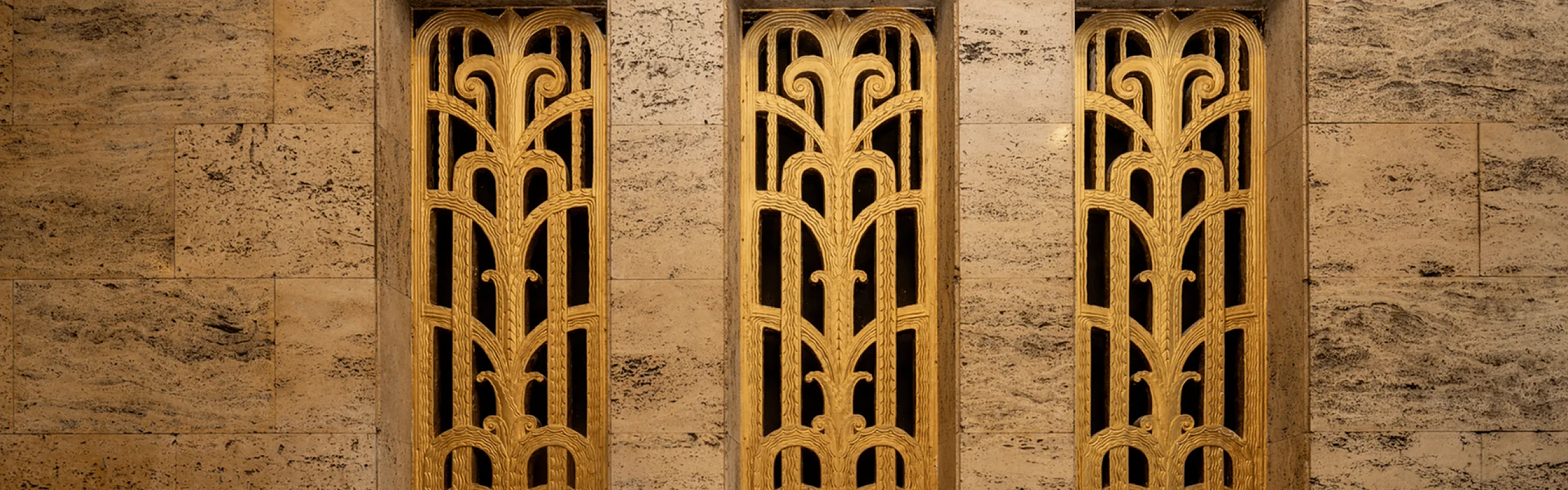 Close-up of a wall featuring intricate golden Art Deco grille accents.