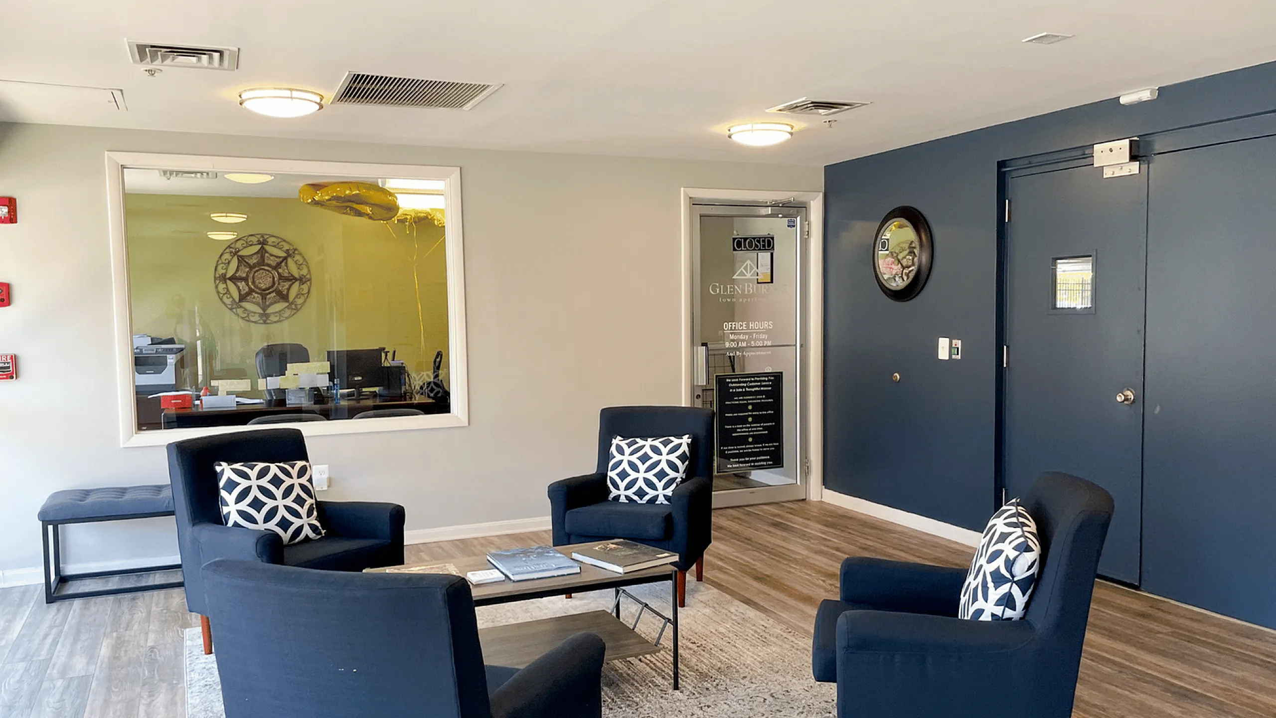 Modern lobby with dark blue chairs, decorative cushions, and stylish wood flooring.