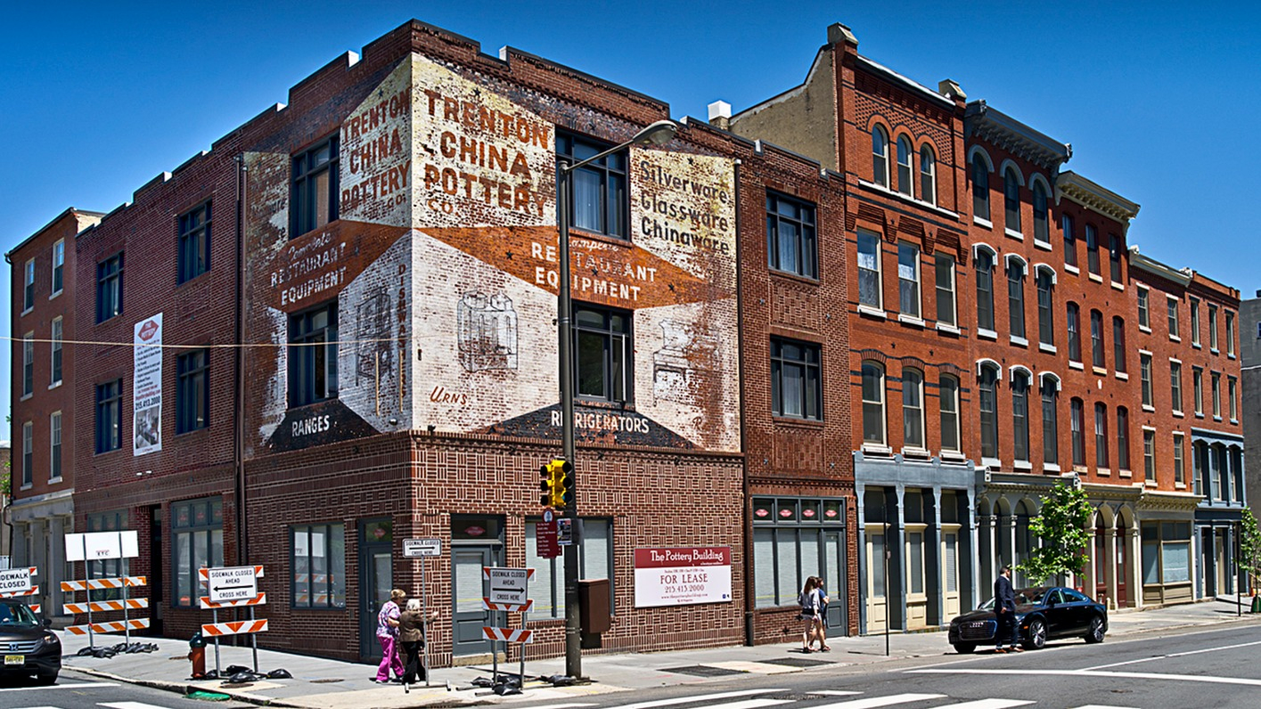 Historic brick building with vintage signage, street view, and bright blue sky.