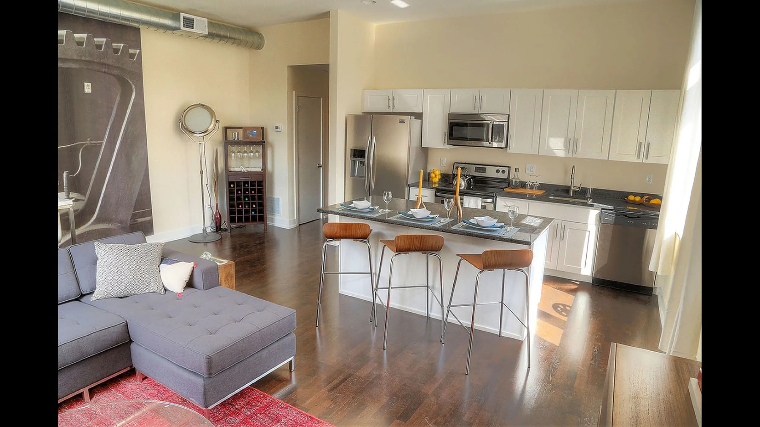 Bright modern kitchen and living area with sleek appliances, bar seating, and stylish decor.