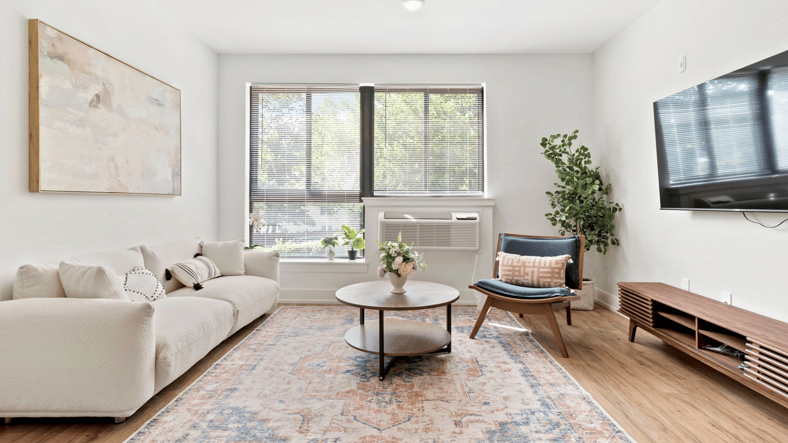 Modern living room with stylish furniture, large windows, and a cozy rug.
