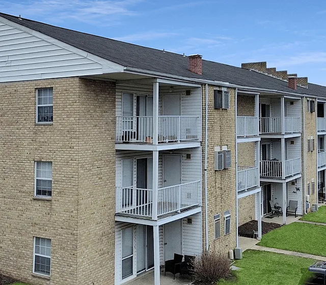 Exterior view of a charming brick apartment building with balconies and well-kept surroundings.