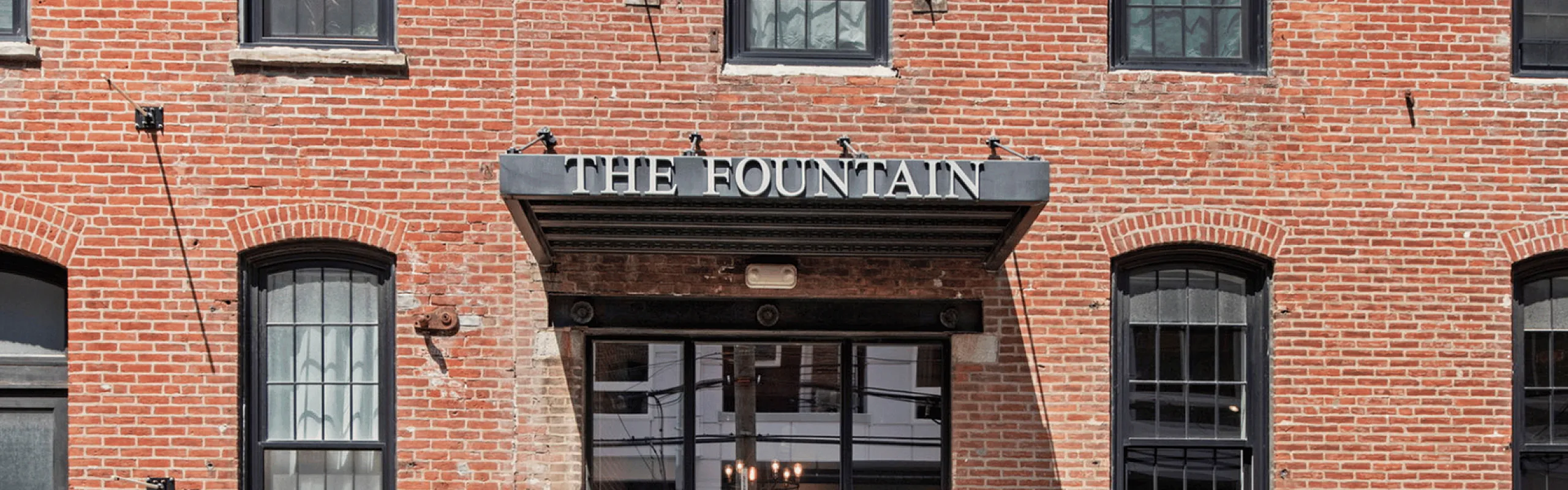 Charming brick exterior of The Fountain building with large windows and a welcoming entrance.