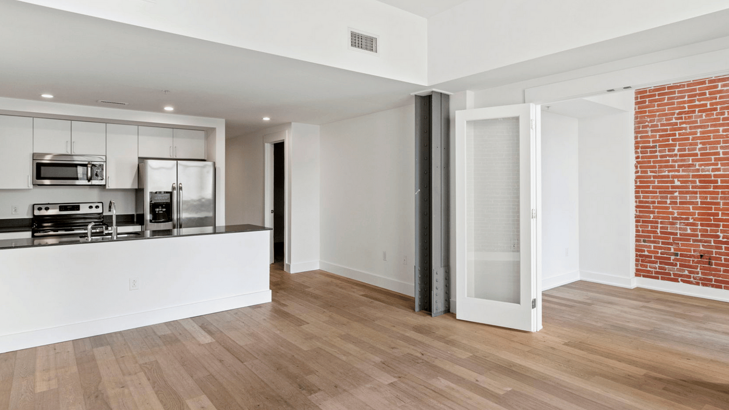 Bright, open-concept living space with hardwood floors and a modern kitchen with stainless steel appliances.