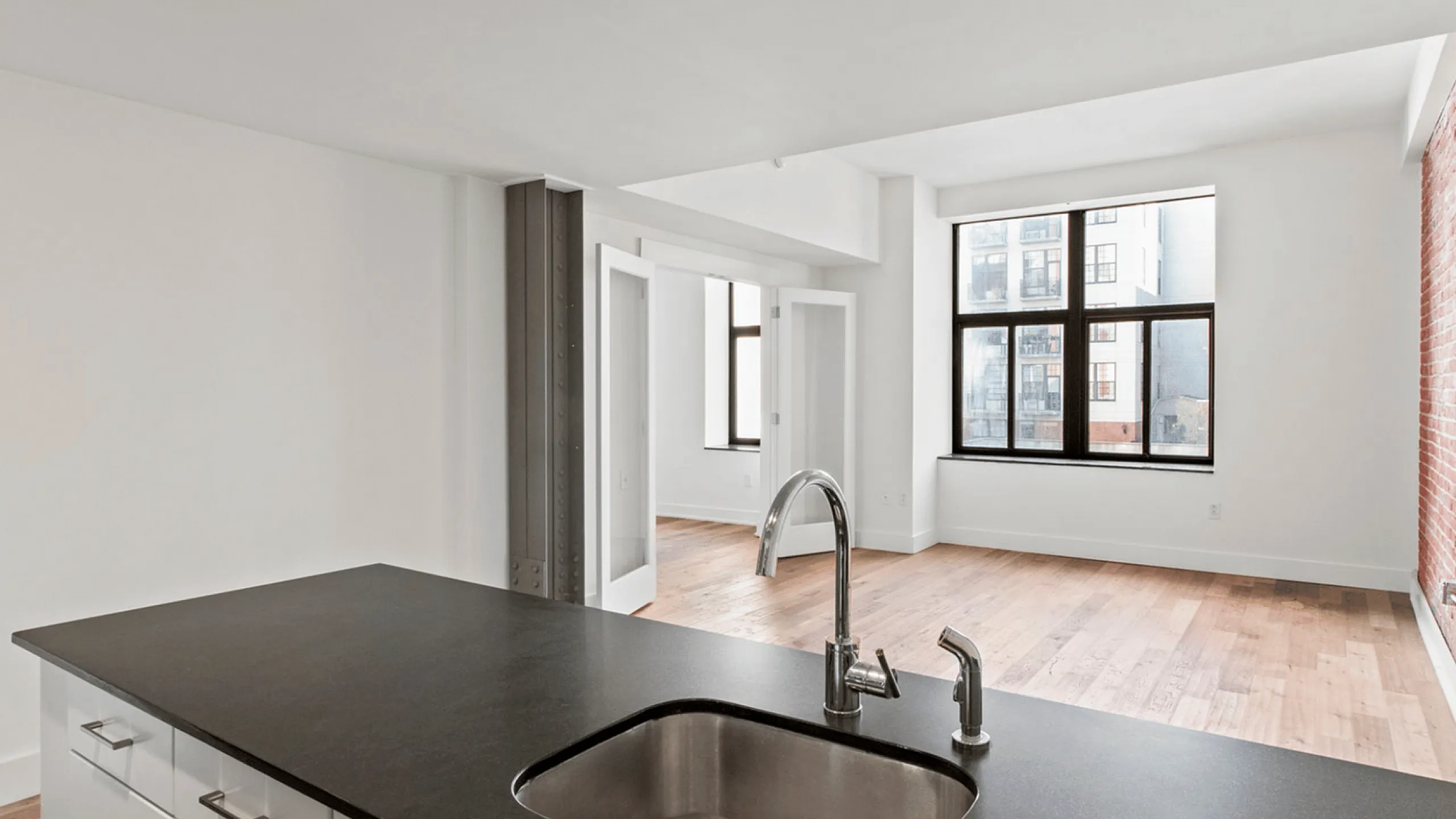 Spacious loft apartment with exposed brick wall, large windows, and modern kitchen island.