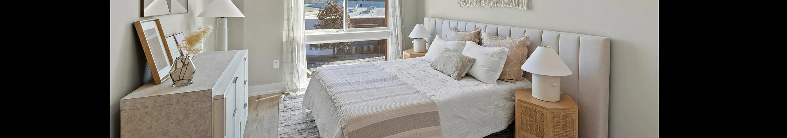 Bright and airy modern bedroom with elegant decor and large window view.