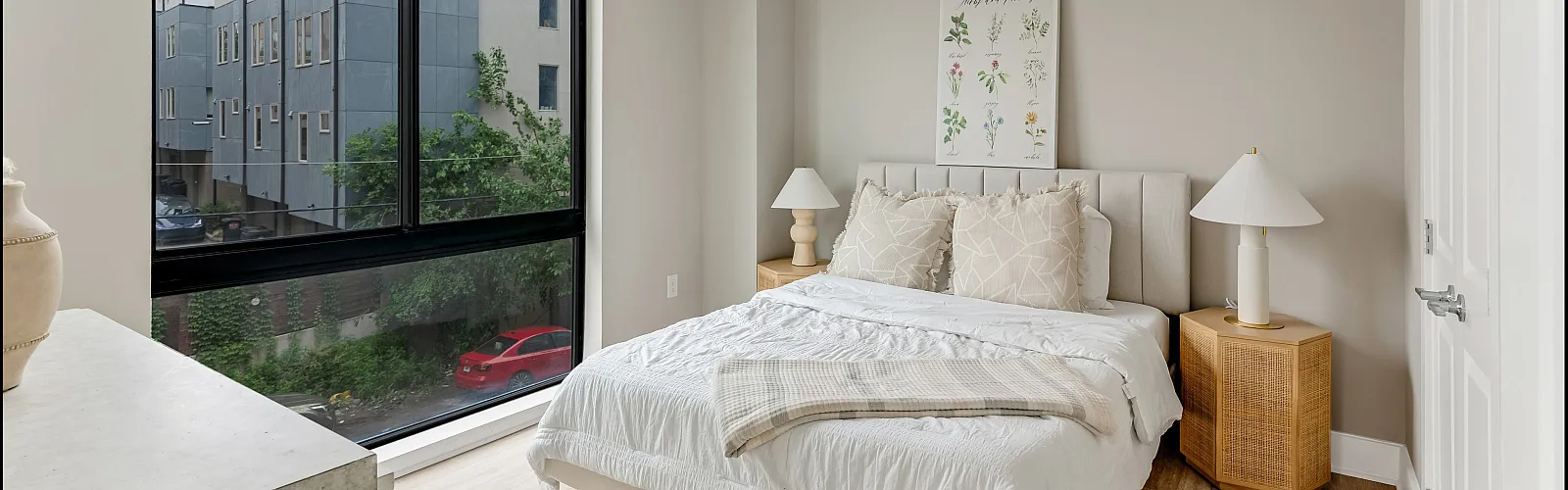 Chic bedroom with cozy bed, large window view, modern decor, and ample natural light.