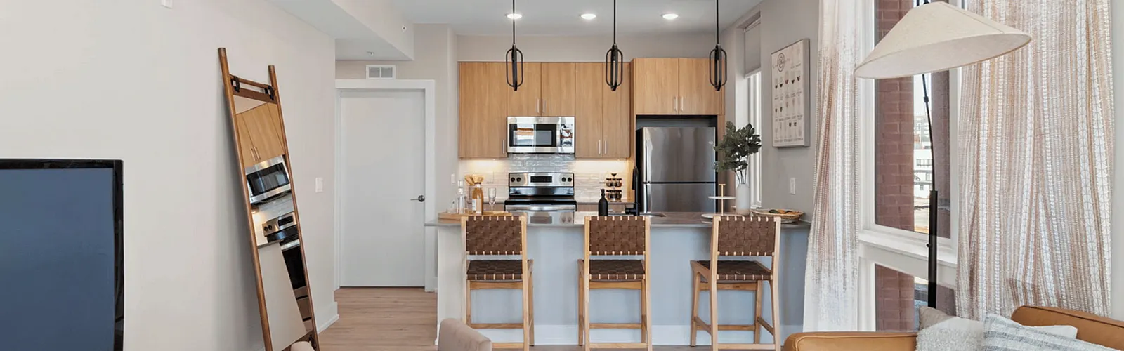 Bright, modern open-concept living area featuring a sleek kitchen with a breakfast bar, stylish pendant lighting, and a cozy lounge space.