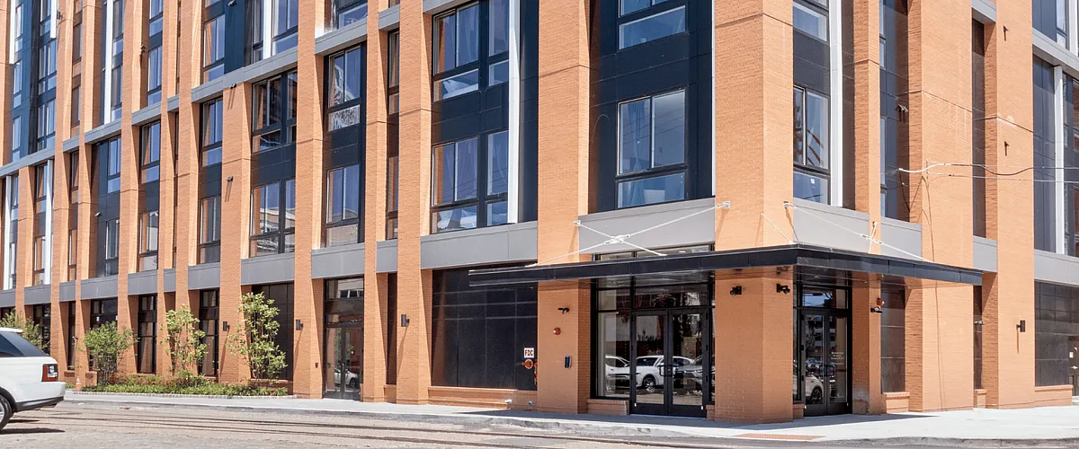 Modern urban apartment building with sleek design featuring large windows and stylish brick facade.