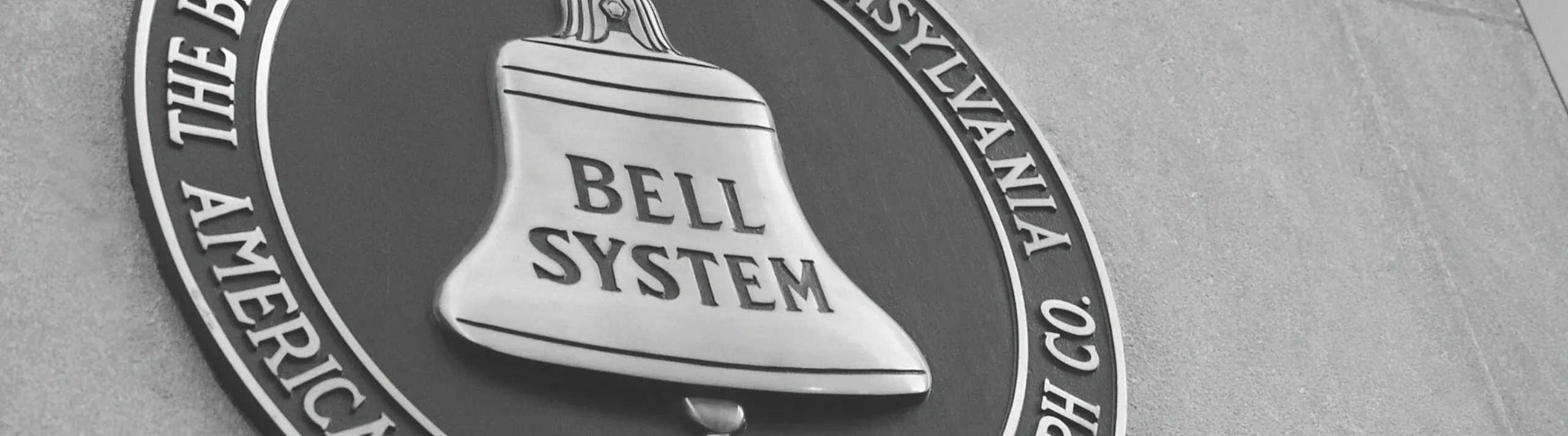 Historic Bell System emblem on a stone wall, featuring a classic bell design and engraved text for a timeless look.