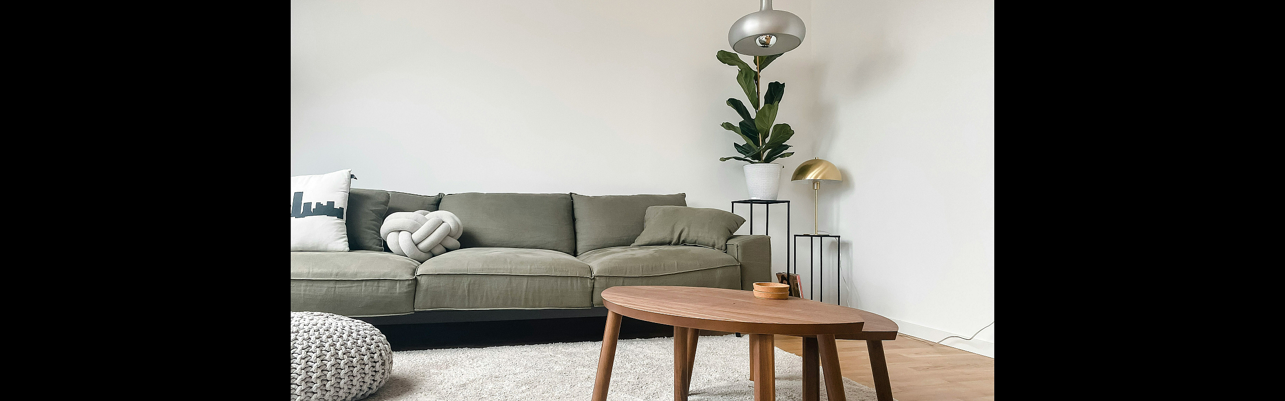 Chic living room with a modern green sofa, cozy textured rug, and elegant wooden coffee table, complemented by stylish decor and ambient lighting.