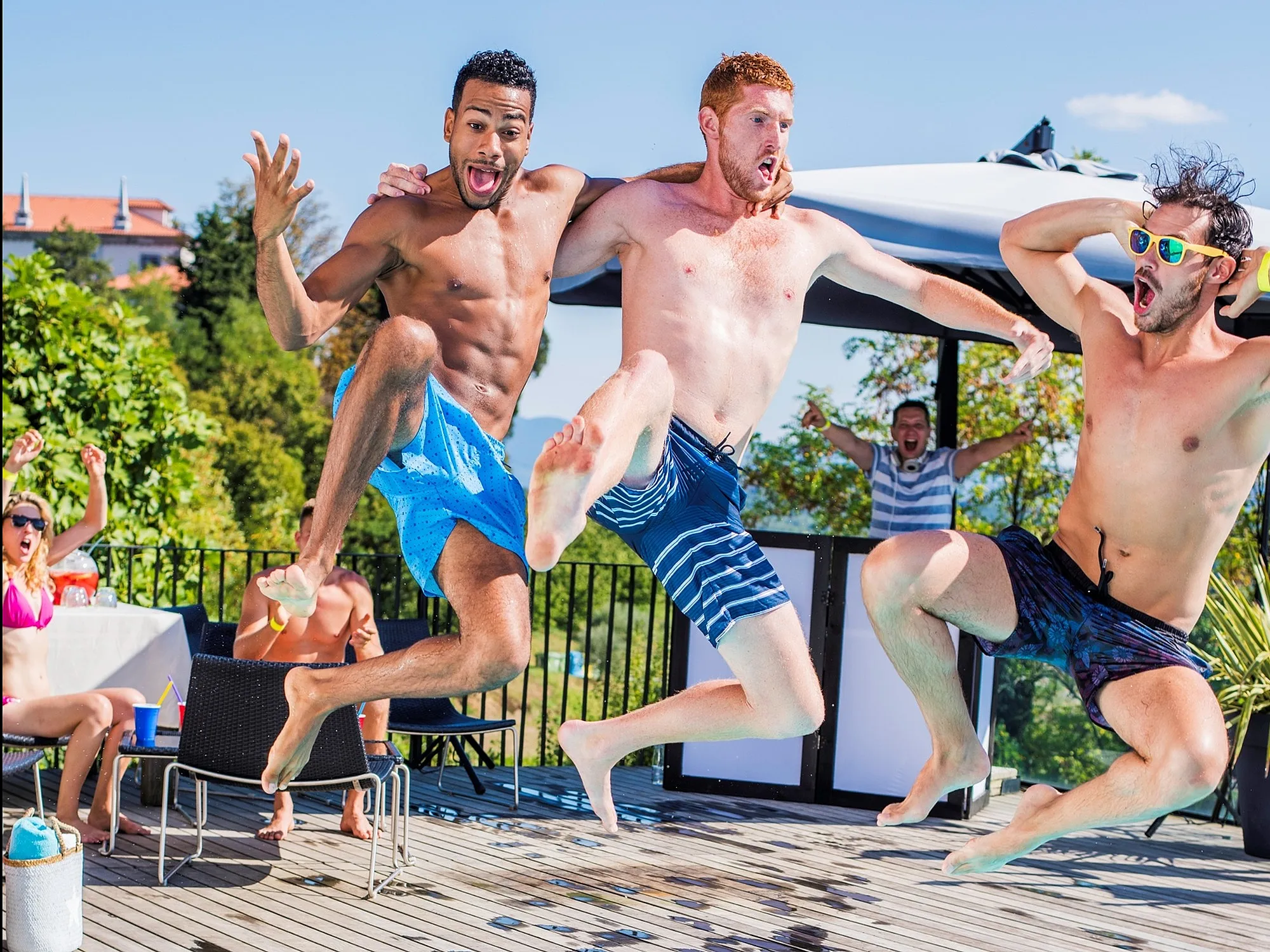 A group of friends joyfully jumping into a pool, capturing a moment of fun and excitement on a sunny day.