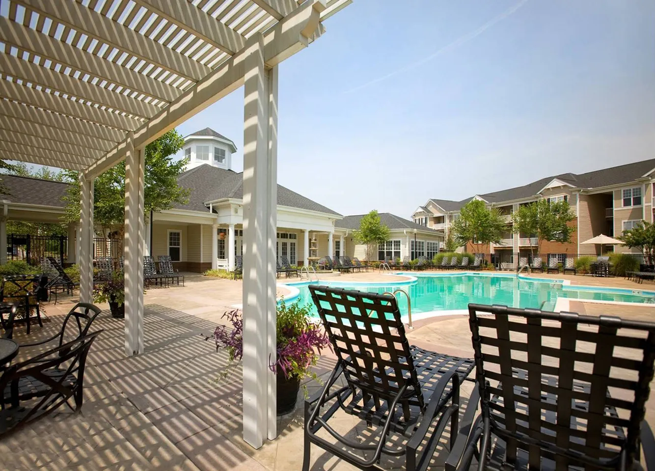 Swimming pool surrounded by a stone patio and lounge chairs at Abberly Place Apartments in Garner, NC