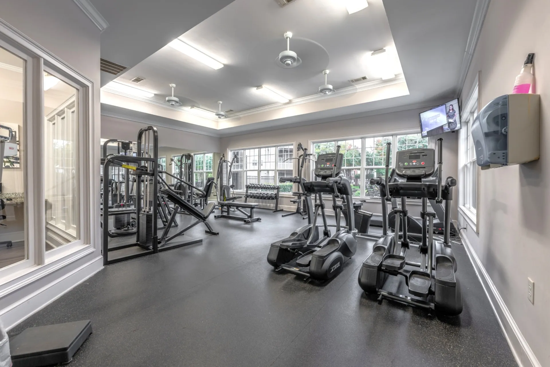 Bright and spacious gym with a variety of equipment including treadmills, elliptical machines, and weight machines at Abberly Place Apartments in Garner, NC