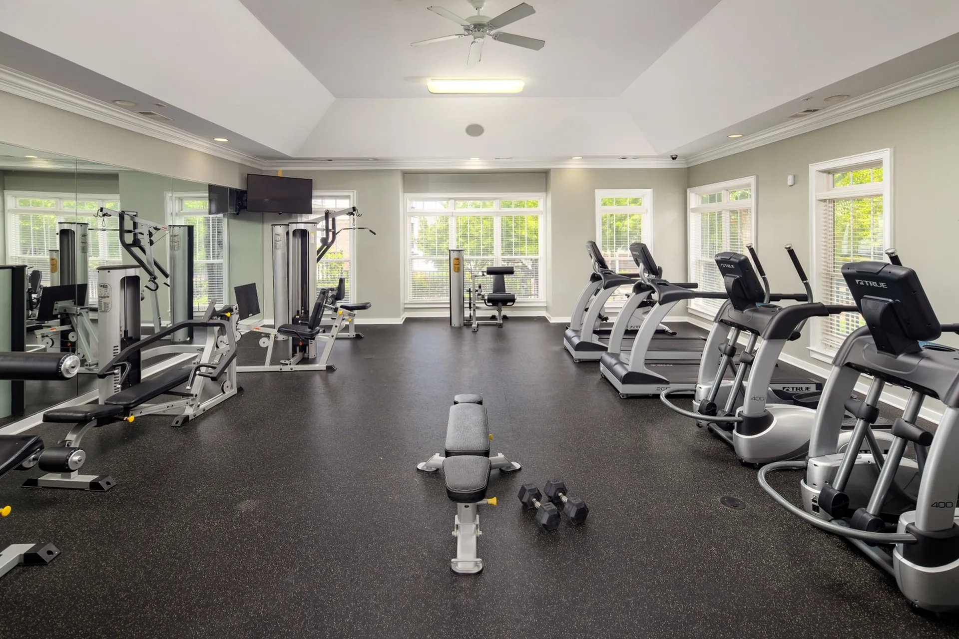 Bright and spacious fitness center featuring a variety of exercise equipment, including treadmills, ellipticals, strength training machines, and free weights at Abberly Place Apartments in Garner, NC