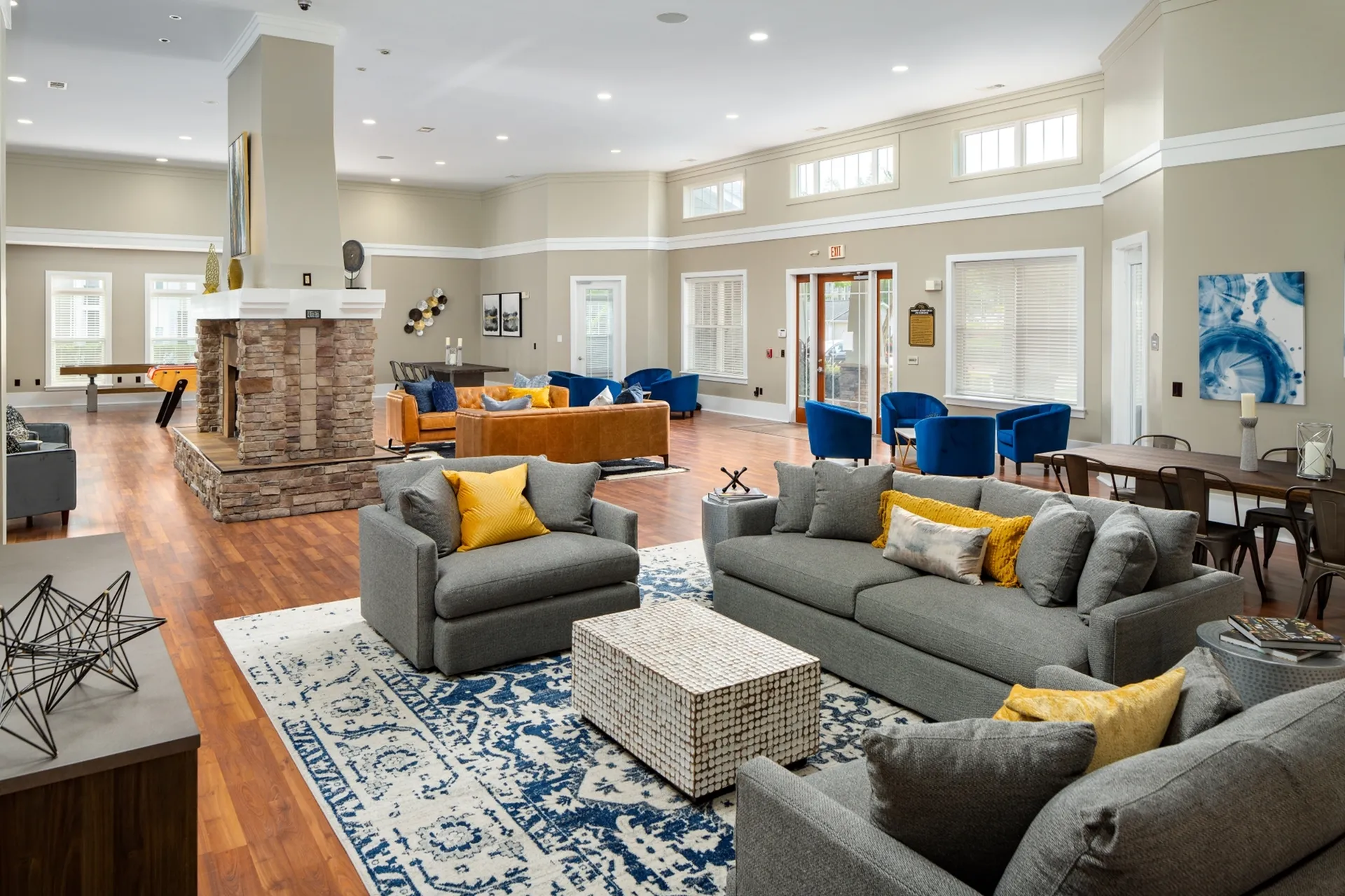 Bright and inviting resident activity center featuring a stone double-sided fireplace, multiple seating areas and large windows allowing natural light to flow in at Abberly Place Apartments in Garner, NC